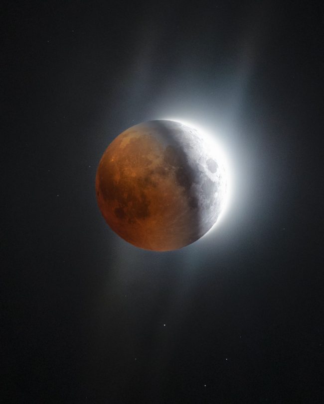 Full moon under eclipse with red tones on left and gray and white on right.