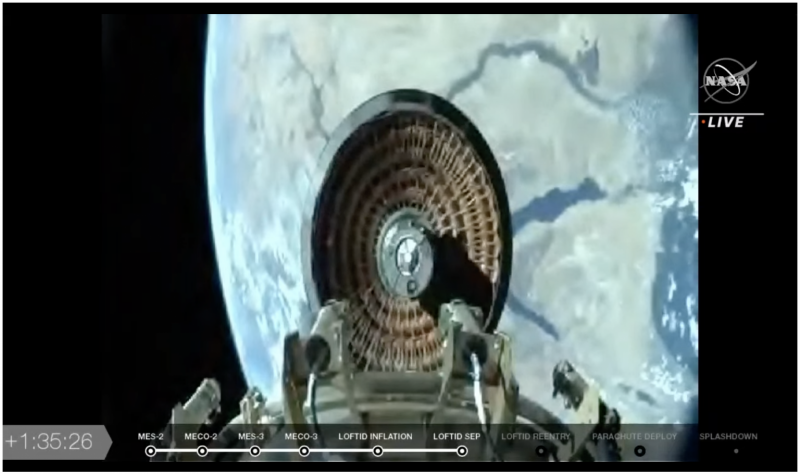 Round heat shield poised high above Earth.