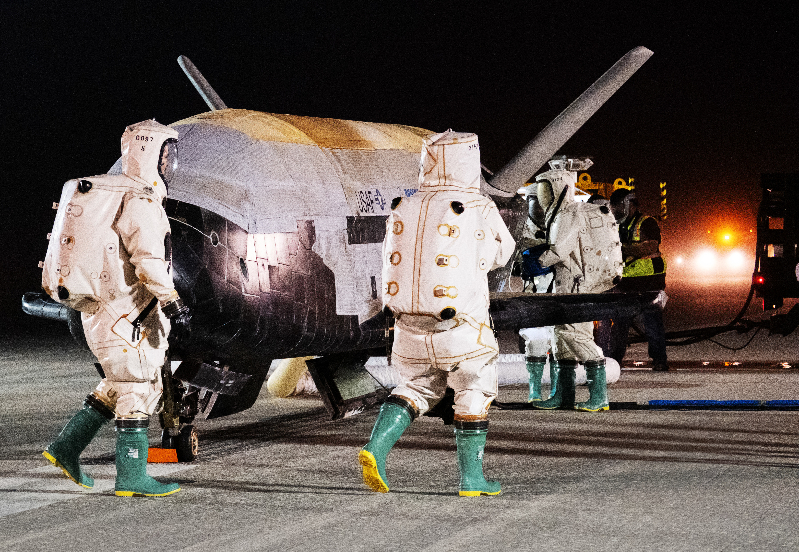 Space force: Small, dirty, bulbous plane with people in hazmat suits around it.