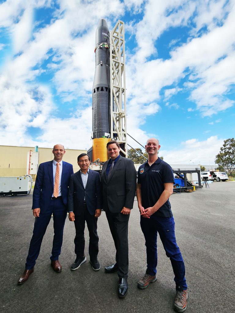 Australia's new launch complex: Men standing with rocket in background.
