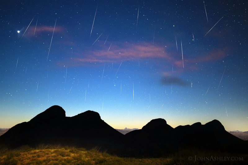 Foreground scenery with bright sky full of meteors.