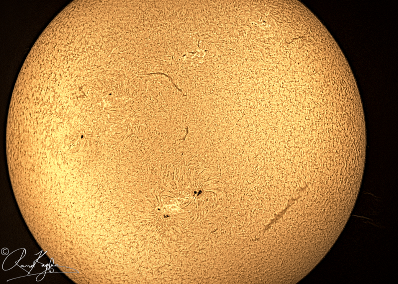 The sun, seen as a sectional orangish sphere with a mottled surface.