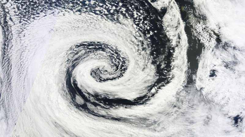 Southern Hemisphere clouds in large spiral over dark water, seen from orbit.