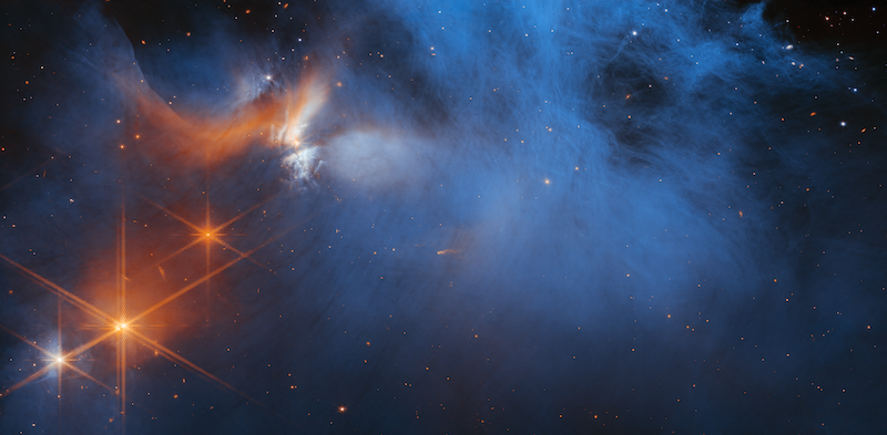 Webb discovered ices: Wispy blue and orange cloud-like structure in space, with scattered stars.