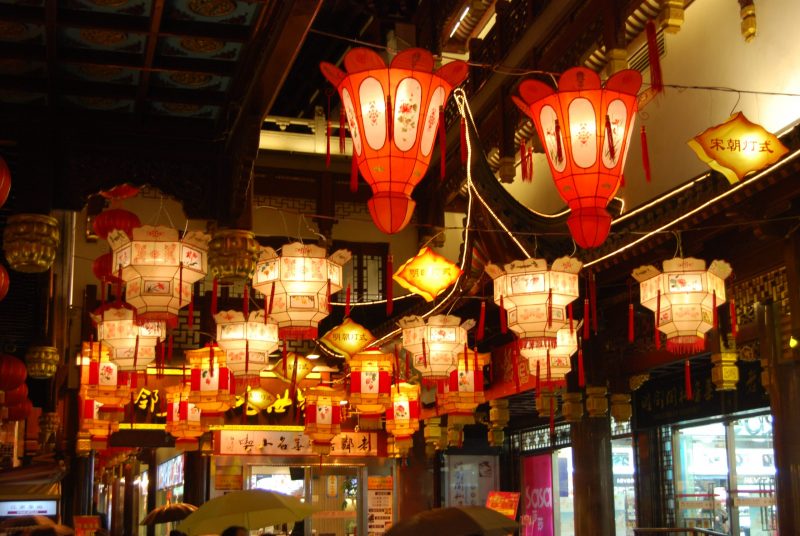 Many glowing lanterns hung above a street at night.