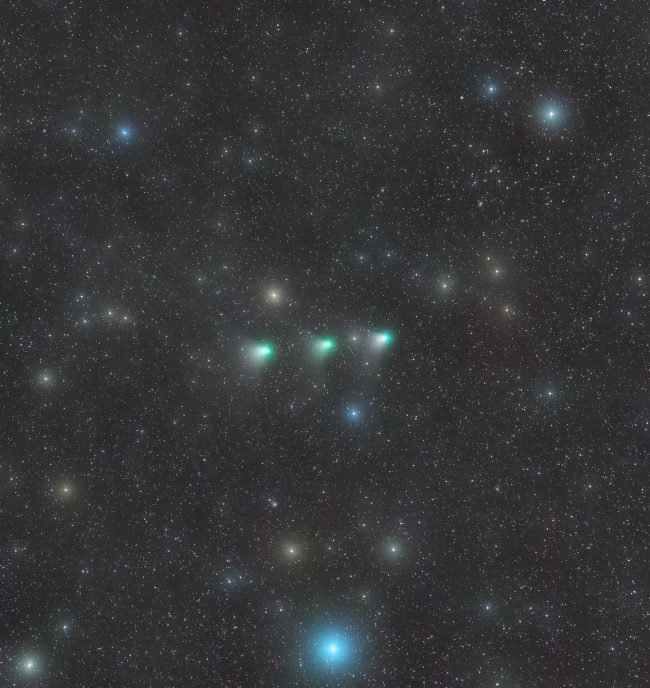 Fuzzy starry view of sky with 3 captures of the greenish comet leaving a trail like Orion's Belt.