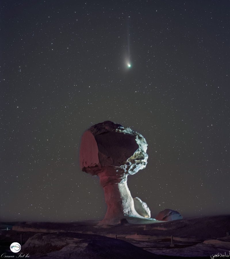 Huge mushroom-shaped rock formation in foreground with comet overhead in a starry sky.