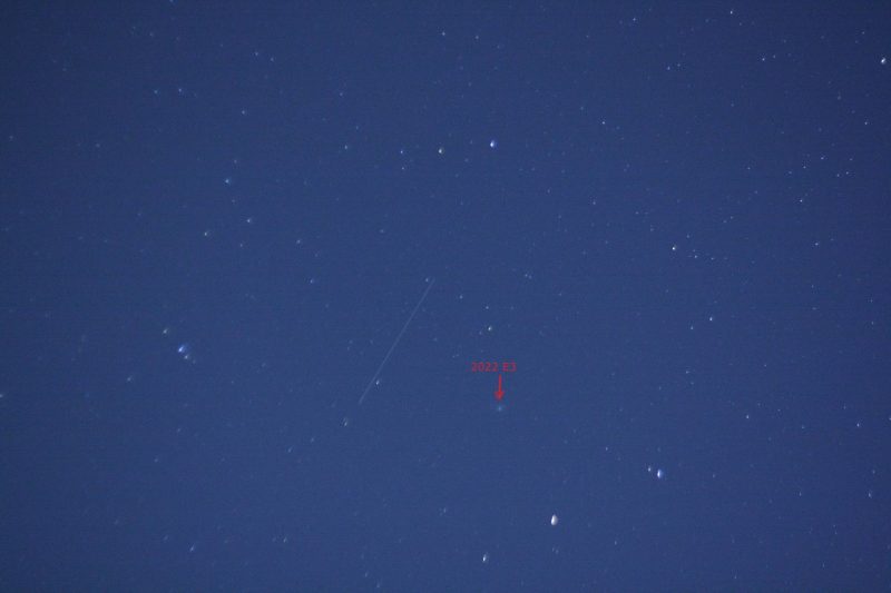 Starry sky with fuzzy green smudge, marked with red arrows, next to a short trail.