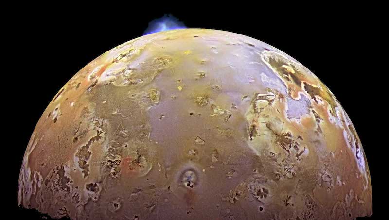 Life on Io: Spotty multi-colored planet-like body with bluish plume bursting outward on the top horizon.