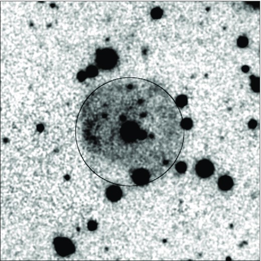 Black-on-white starfield image, with big round shell of gas in the middle.