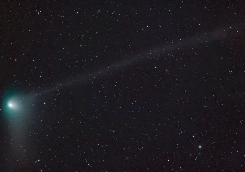 A large, green comet over a background of distant stars.