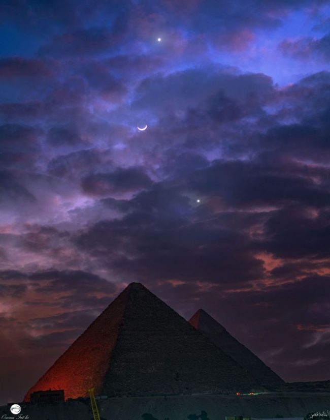 Two bright dots and a crescent moon. Huge pyramid below. Blue sky at the top and pink at the bottom.