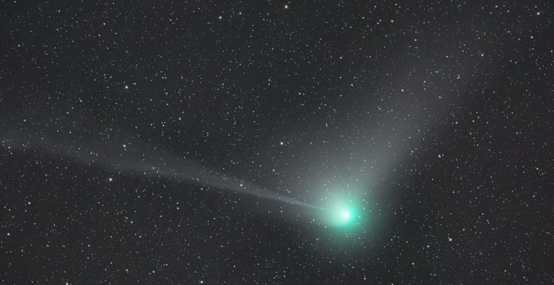 A large, green comet over a background of distant stars.