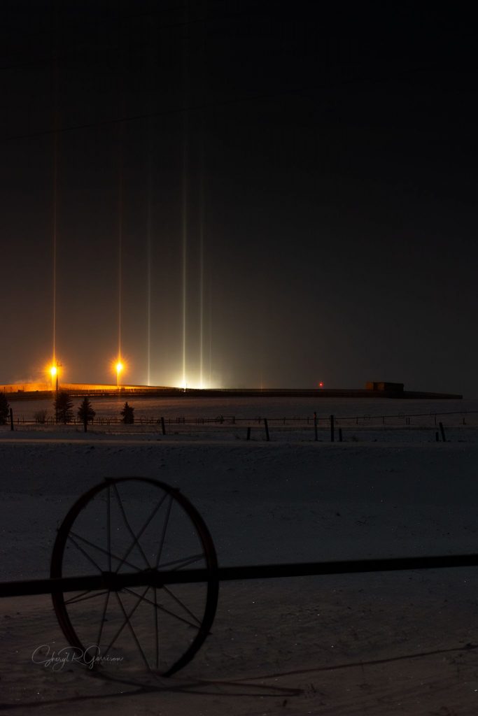 Light pillars in the distance with metal wheel in foreground.