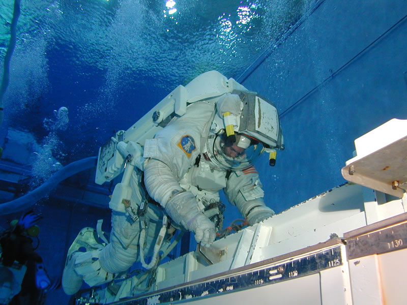 Astronaut in a white spacesuit training underwater.