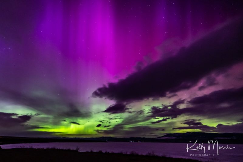 Purple and yellowish green lights the sky behind a few dark clouds.