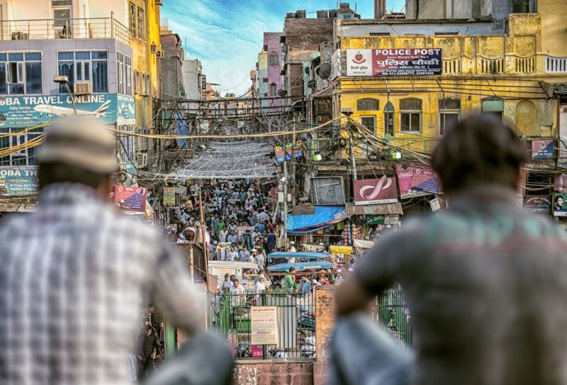 Most populous country: Out of focus foreground of 2 men looking at crowded street below.