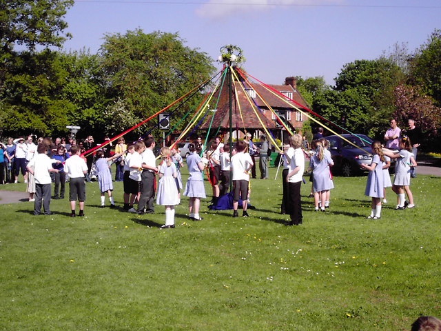 May Day: Group of children holding ribbons off a maypole.