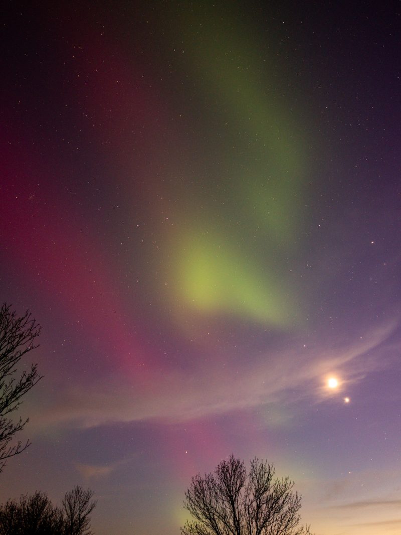 Pink and green blobs of aurora light. 2 bright spots at the bottom right, one is bigger than the other.