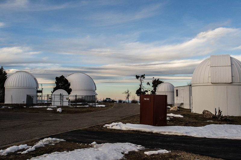 Help spot asteroids: White observatory domes with some snow on the ground and a daytime partly cloudy sky.