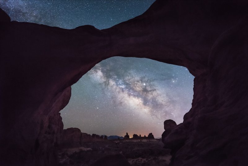 Dark rock forming an opening with the Milky Way in the background.