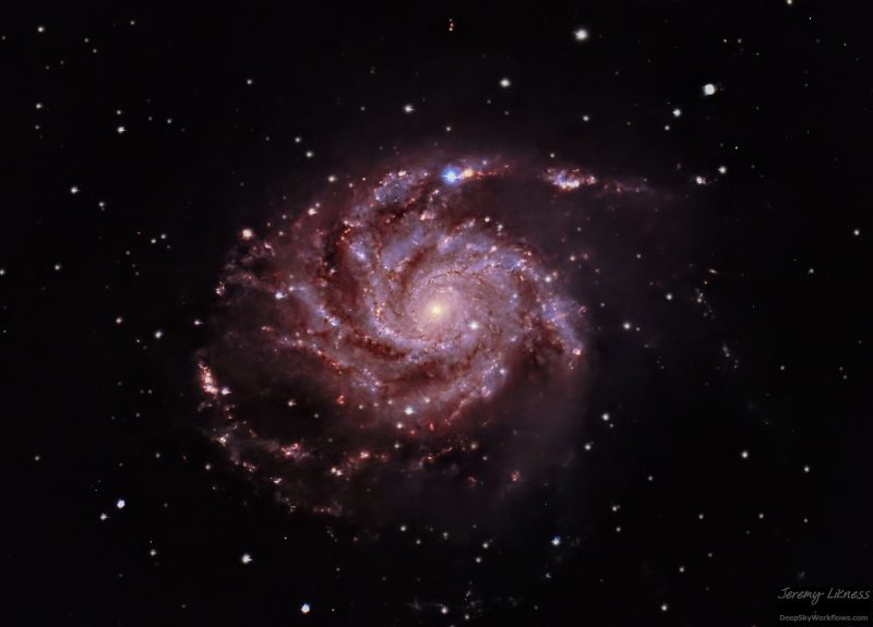 A purplish pinwheel spiral made of dust and light with one bright bluish light at top.