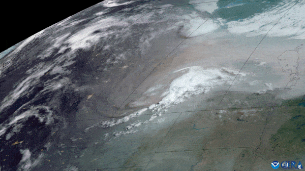 A counterclockwise swirl made of smoke and clouds spins over southern Canada, North Dakota.