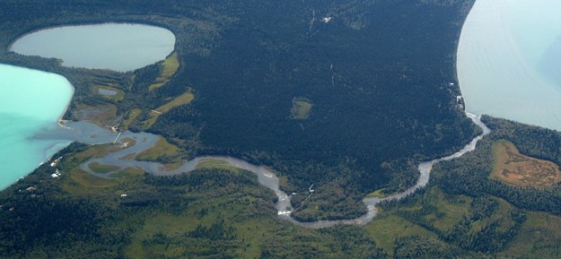 Aerial view of land with almost circular lakes on left and right and river snaking through middle.