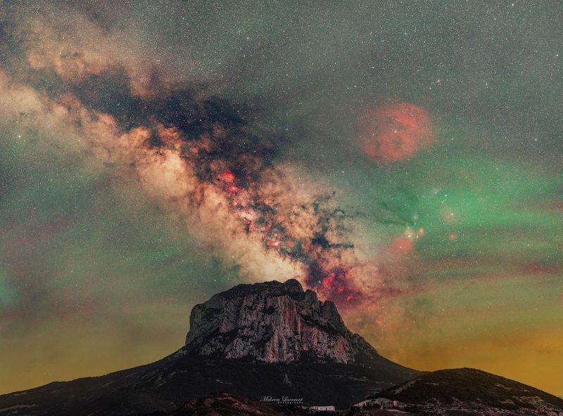 Airglow: A photograph showing a mountain and the Milky Way and green sky.