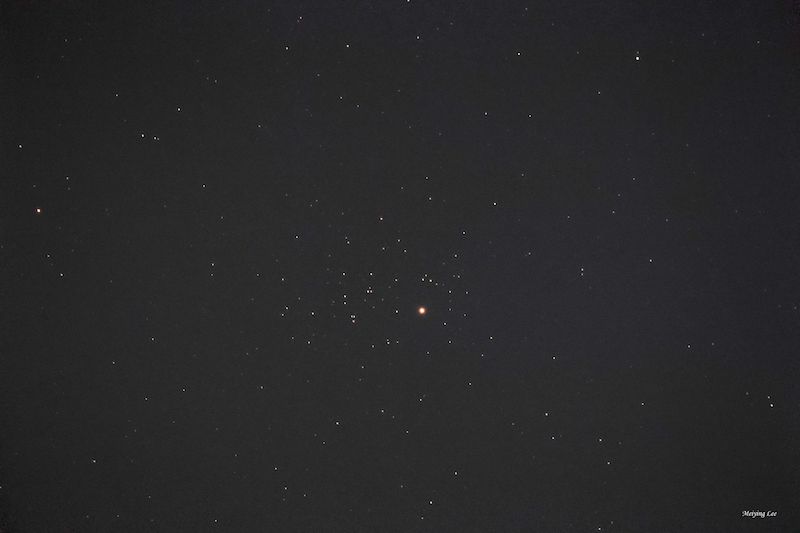 Scattered dim stars on black sky with reddish dot of Mars.