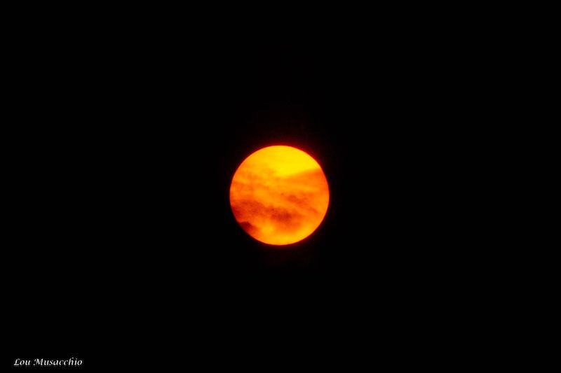 Red suns and moons: Dark yellow sun with big orange to red streaks across it, on black background.