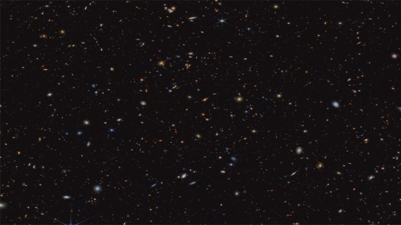 45,000 baby galaxies: Small spirals and irregular shaped spots (in white, blue, yellow and orange) on a black background.