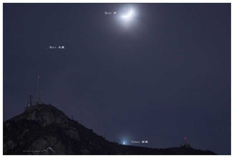 Bright moon at top, smaller bright Venus at bottom, little red Mars at top left. There is a mountain at bottom left.