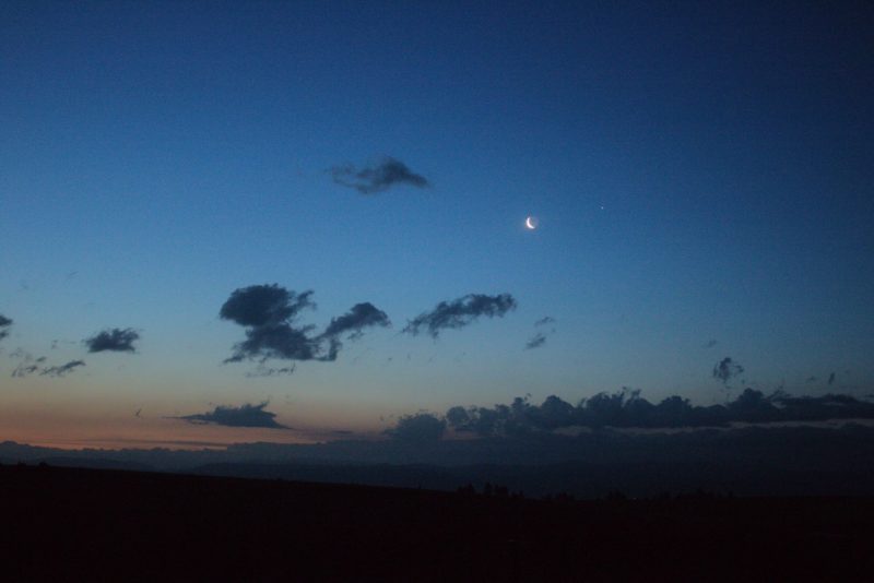 Moon and Jupiter in a dawn sky. There is orange in the horizon.