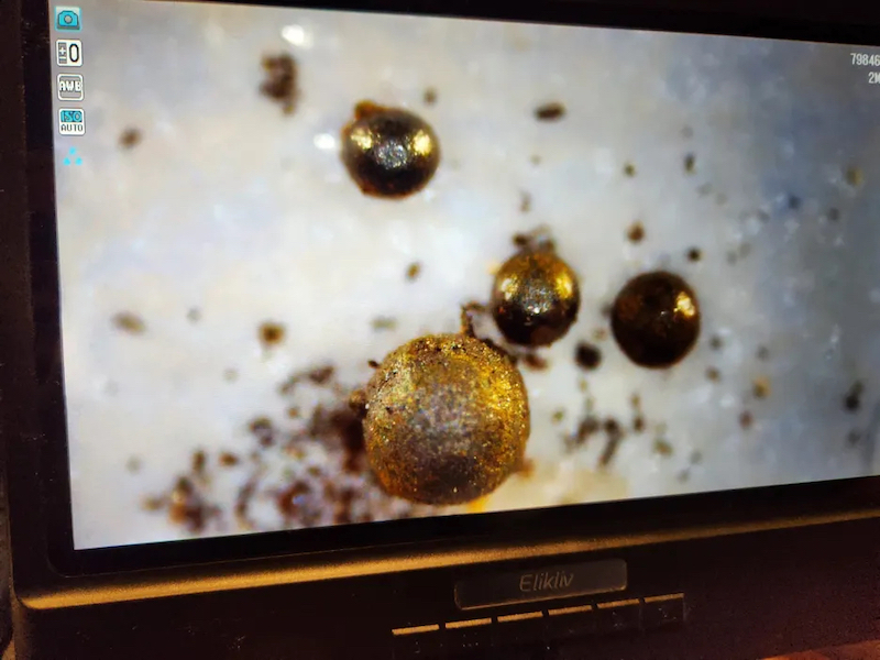 Vivid photo of 4 metallic, gold-colored, rough-textured spheres on a computer screen.