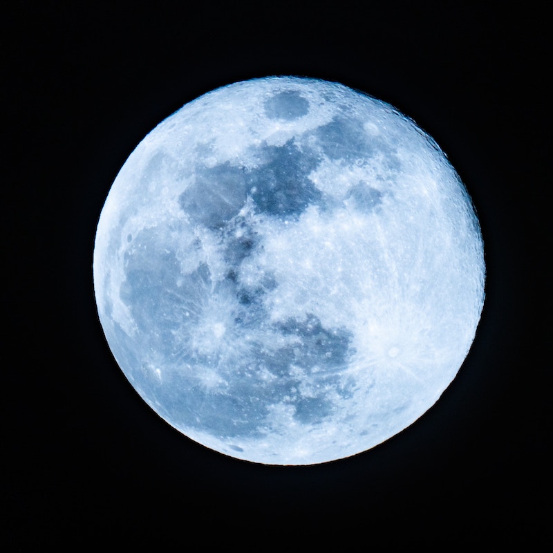 Full moon with a blue hue with black background.