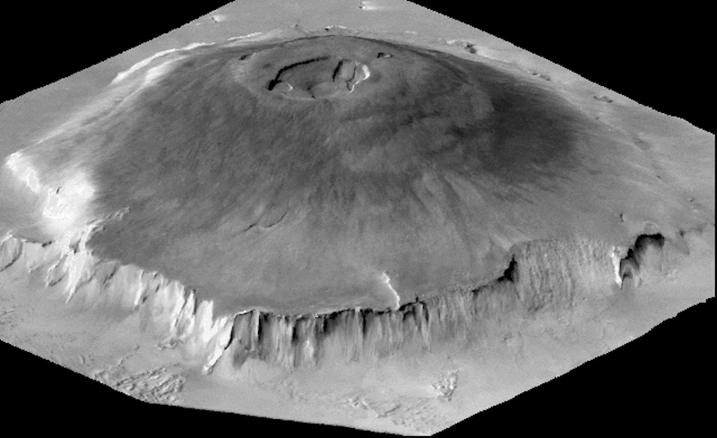Black and white oblique orbital view of conical mountain with craters on the top.