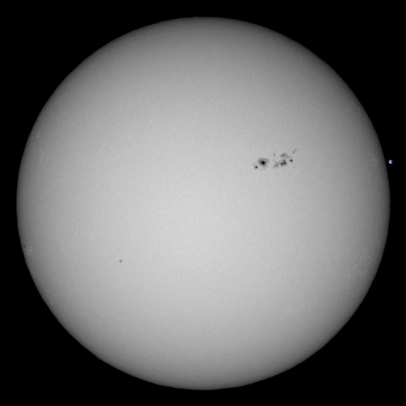 The sun, seen as a large white sphere with small dark spots.