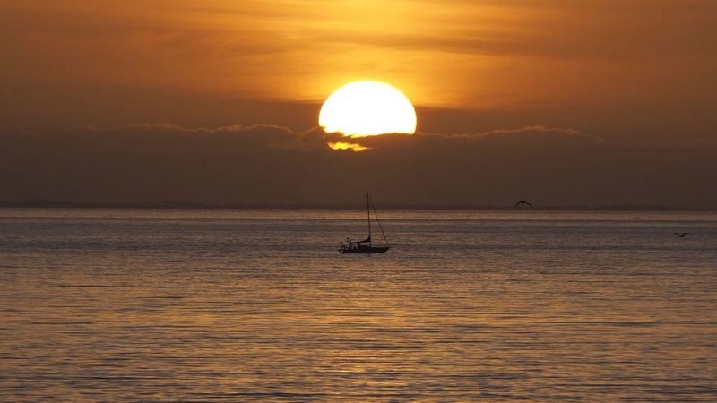 Record highs at sea: Ocean, sunset, and a lone boat.