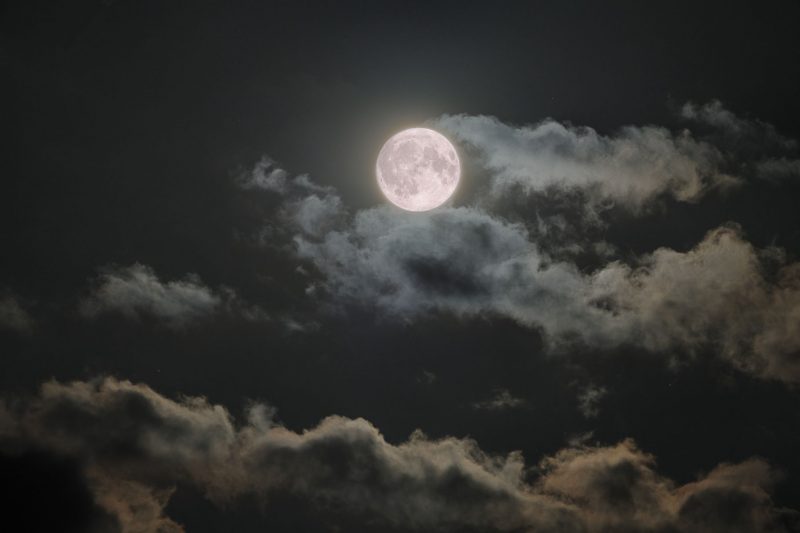 Bright white moon with clear and visible features, and clouds behind it.
