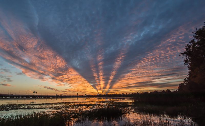 Layer of clouds over a surface of water. The orange and blue colors in the clouds are reflected in the water.