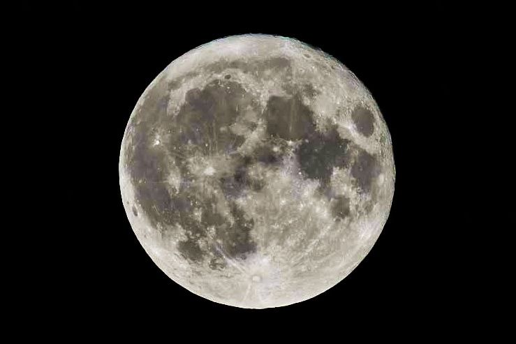 Large round full moon, white with gray areas, against black background.