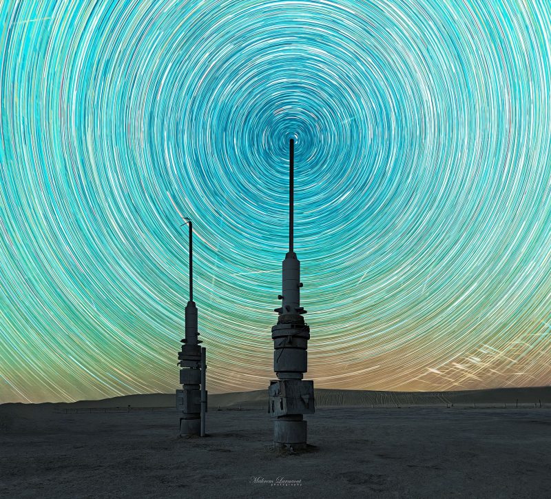 Night sky of Star Wars: Star trails with 2 spire like towers in desert landscape.