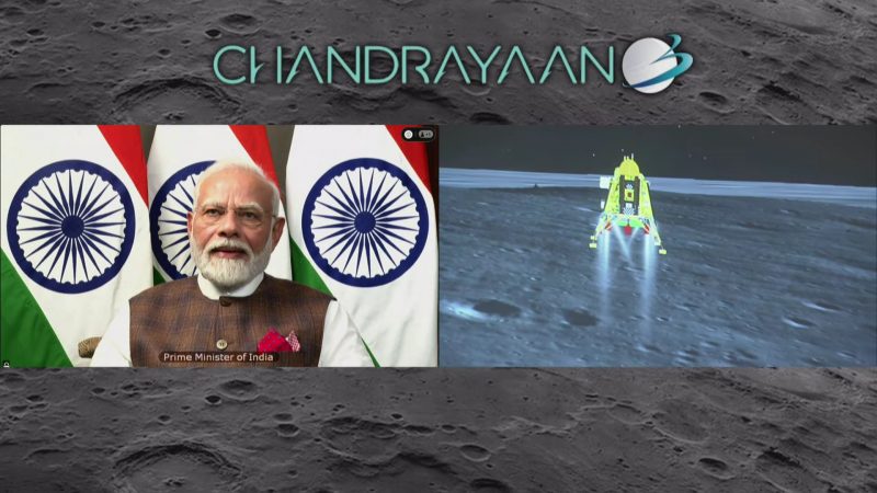 Man with white hair and beard next to CGI image of lander nearing moon.