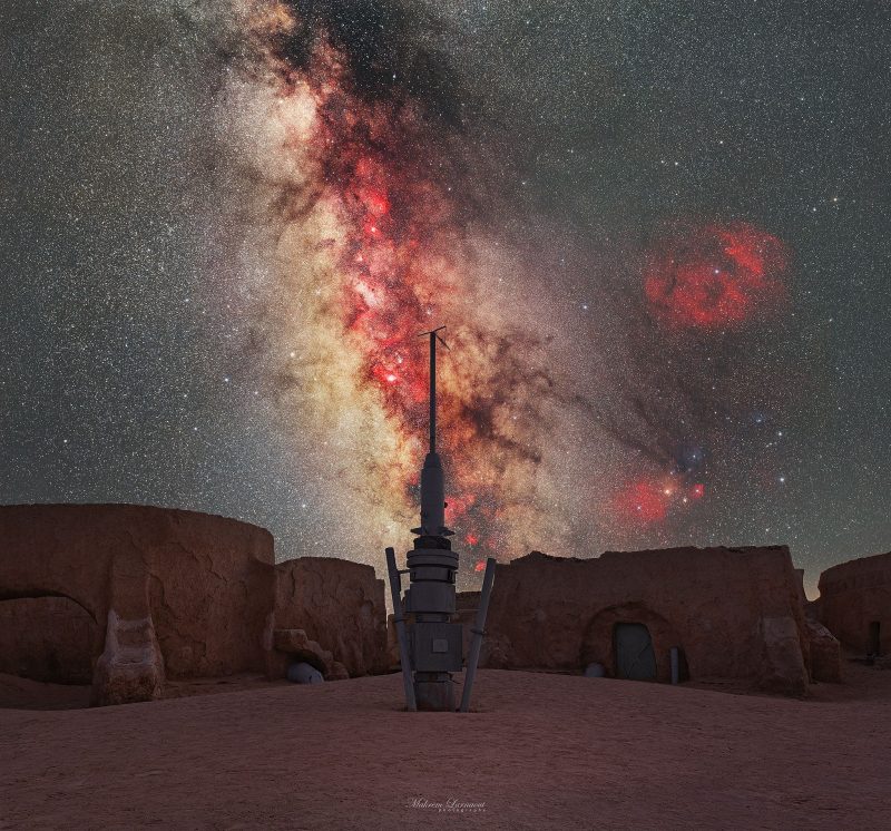 Milky Way behind spire with buildings in foreground.