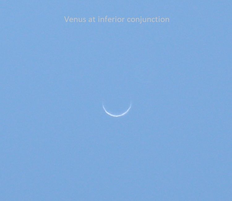 Large, very thin crescent Venus in a light blue sky.
