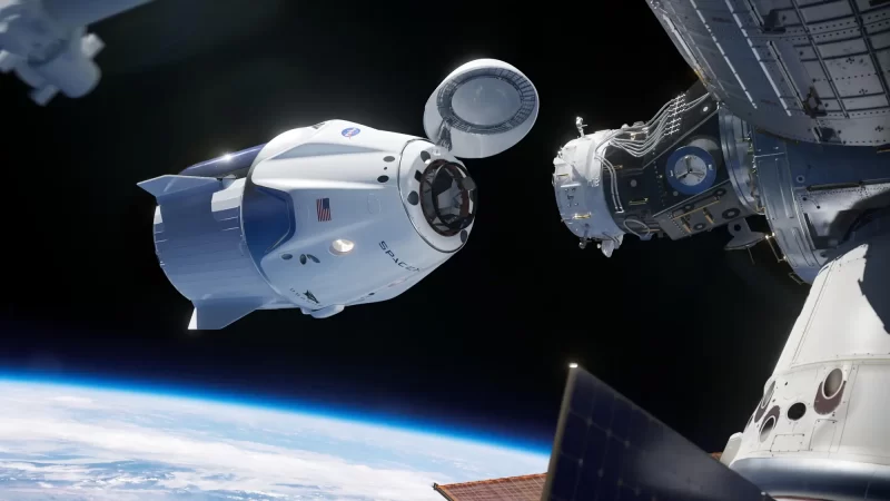 Sunlit, bullet-shaped white space capsule approaching a cylindrical dock, with Earth below.