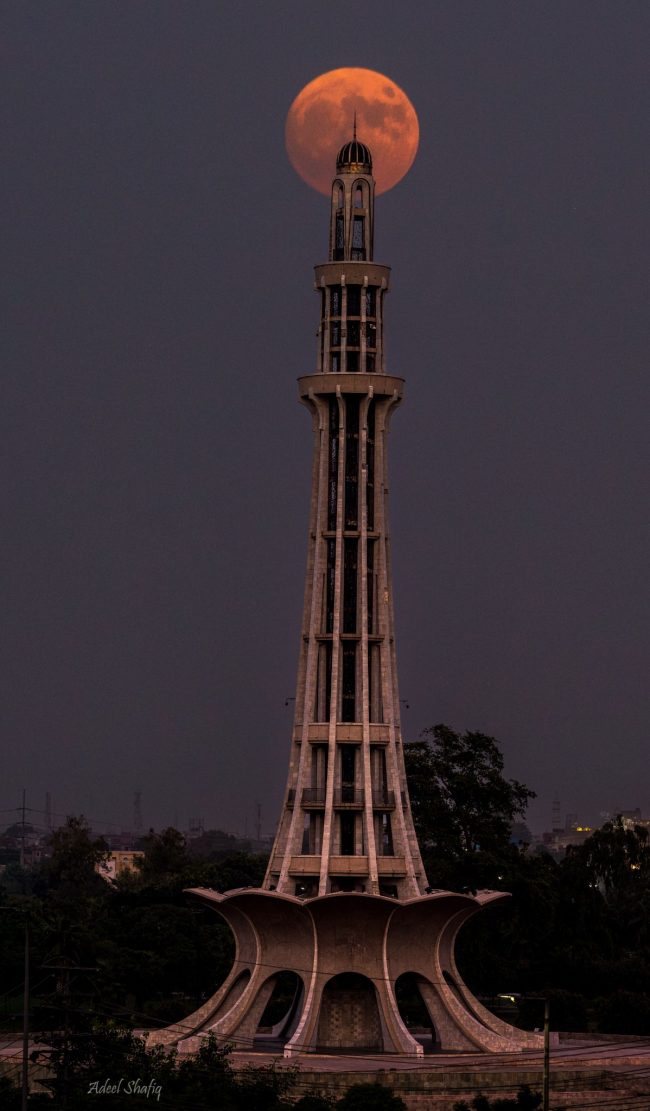 Tall tower with supermoon behind the top spire.