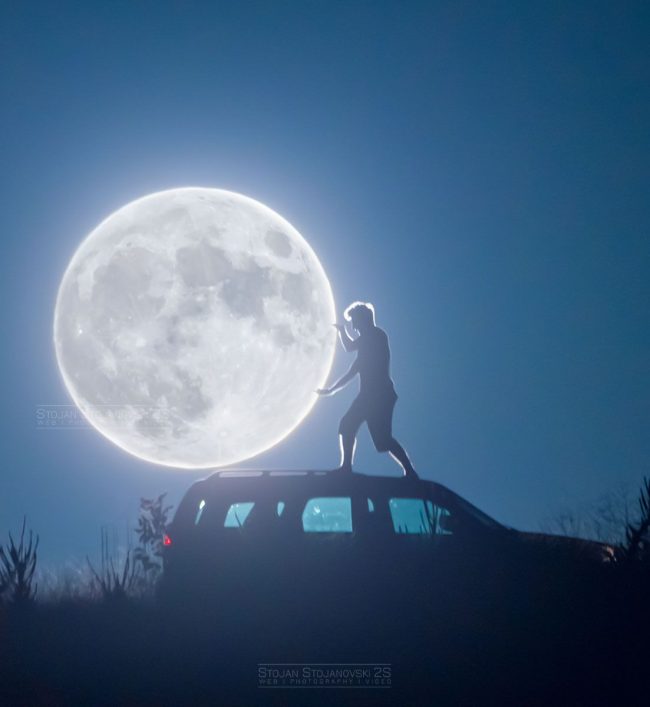 Stargazing tips: Man standing on a car with hands out as if touching a huge glowing white full moon.