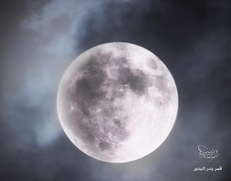 Bright white, slightly hazy supermoon with puffy, translucent clouds.